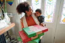 Мати з дитиною дочка отримує доставку піци біля вхідних дверей — стокове фото