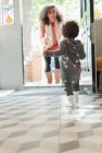 Felice figlia del bambino che corre a salutare la madre alla porta — Foto stock