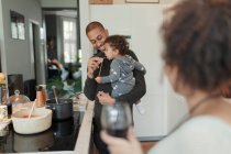 Pai cozinhar e alimentar a filha bebê no fogão da cozinha — Fotografia de Stock