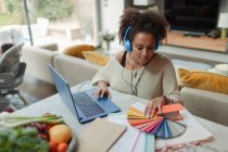 Designer féminin avec des échantillons de couleur de travail de la maison à l'ordinateur portable — Photo de stock