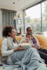 Família assistindo filme e comer pipocas no sofá da sala de estar — Fotografia de Stock