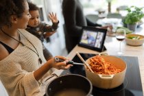 Mutter und Tochter kochen Spaghetti und unterhalten sich per Video — Stockfoto