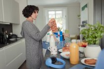 Женщина разгружает продукты на кухонном столе — стоковое фото