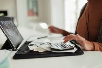 Frau mit Taschenrechner und Quittungen bezahlt Rechnungen mit digitalem Tablet — Stockfoto