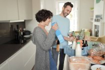 Glückliches Paar packt Lebensmittellieferung an der Küchentheke aus — Stockfoto