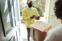 Woman receiving packages from delivery man in face mask at front door — Stock Photo