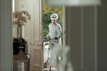 Чоловік з велосипедом повертається додому через вхідні двері — стокове фото