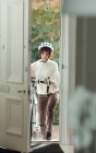 Donna con bicicletta che torna a casa attraverso la porta d'ingresso — Foto stock