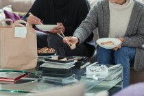 Пара насолоджується їжею з паличками у вітальні — стокове фото