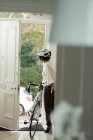 Woman with bicycle returning home through front door — Stock Photo