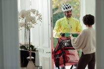 Friendly courier delivering pizza to woman at front door — Stock Photo