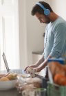 Mann mit Kopfhörer arbeitet von zu Hause aus am Laptop in der Morgenküche — Stockfoto