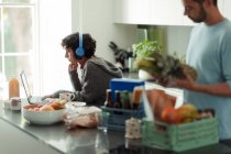 Ehepaar arbeitet von zu Hause aus und entlädt Lebensmittel in Küche — Stockfoto