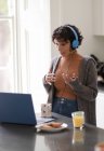 Жінка з навушниками на відео виклик працює з дому на ноутбуці — стокове фото