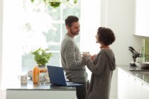 Happy couple talking and working in morning kitchen — Stock Photo
