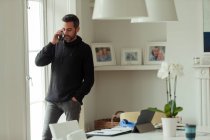 Mann arbeitet von zu Hause aus und telefoniert am Fenster mit Smartphone — Stockfoto