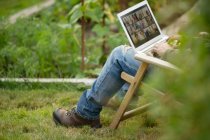 Человек, работающий за ноутбуком в огороде — стоковое фото
