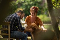 Coppia felice con cane Golden Retriever al tavolo da giardino — Foto stock