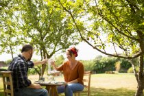 Happy couple toasting water glasses at table in sunny summer garden — Stock Photo