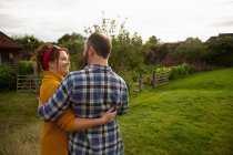 Happy affectionate couple hugging in idyllic cottage garden — Stock Photo