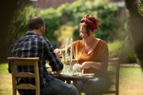 Счастливая пара за столом в летнем саду — стоковое фото