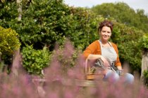 Ritratto donna felice prendersi una pausa dal giardinaggio in giardino soleggiato — Foto stock