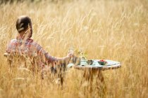 Человек расслабляется за столом в солнечной летней высокой траве — стоковое фото
