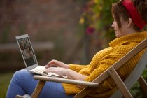 Woman using laptop in lawn chair — Stock Photo