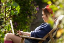 Femme utilisant un ordinateur portable dans un jardin d'été ensoleillé — Photo de stock