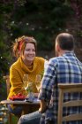 Casal feliz desfrutando de champanhe e groselhas vermelhas na mesa de jardim — Fotografia de Stock