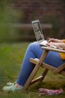 Woman using laptop in garden lawn chair — Stock Photo