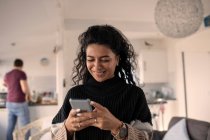 Щаслива жінка використовує смартфон вдома — стокове фото