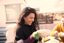 Donna felice godendo zuppa sul patio soleggiato — Foto stock