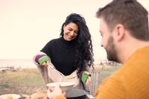 Mulher feliz servindo chowder para namorado no pátio da praia — Fotografia de Stock