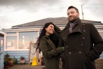 Retrato feliz pareja en abrigos de invierno fuera de casa - foto de stock
