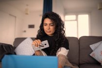 Woman working from home with smart phone and laptop on sofa — Stock Photo
