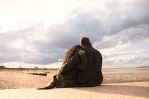 Heiteres, liebevolles Paar umarmt sich am sonnigen, ruhigen Winterstrand — Stockfoto