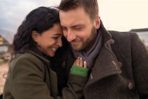 Счастливая любящая пара в зимних пальто, обнимающая — стоковое фото