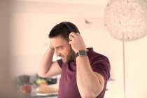 Homem com relógio inteligente e fones de ouvido ouvindo música em casa — Fotografia de Stock
