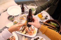Casal brindar vinho e cerveja ao almoço de frutos do mar — Fotografia de Stock