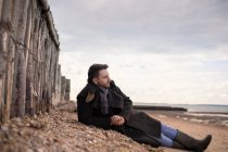 Спокойный мужчина в зимнем пальто отдыхает на пляже — стоковое фото