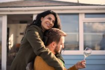 Happy couple hugging and drinking wine on patio — Stock Photo