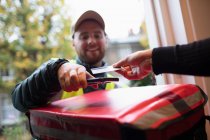 Cliente pagando homem de entrega com cartão sem contato na porta da frente — Fotografia de Stock