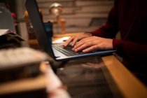 Закрыть молодой человек, работающий за ноутбуком на столе в домашнем офисе — стоковое фото