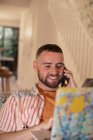 Lächelnder junger Mann telefoniert am Laptop — Stockfoto