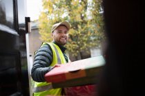 Friendly delivery man delivering pizza at front door — Stock Photo