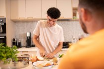 Молодий чоловік готує ріжучу цибулю на кухні — стокове фото