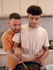 Afetuoso gay masculino casal cozinhar e abraço no cozinha — Fotografia de Stock