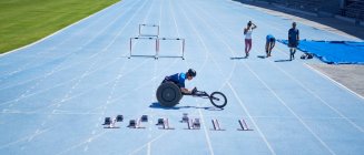 Atleta en silla de ruedas preparándose en la soleada pista deportiva azul - foto de stock