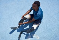 Unterschenkelamputierter Sprinter bereitet sich auf blauer Sportbahn vor — Stockfoto
